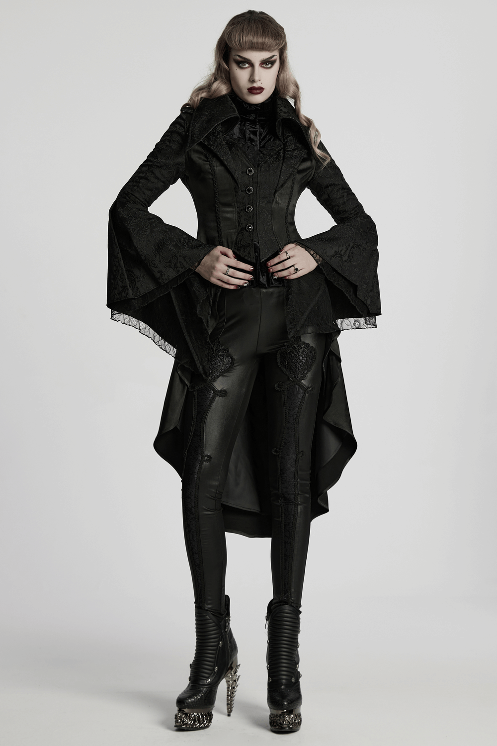Chic high-low tailcoat featuring jacquard lace and buttons, styled with sleek black leggings and edgy heels.