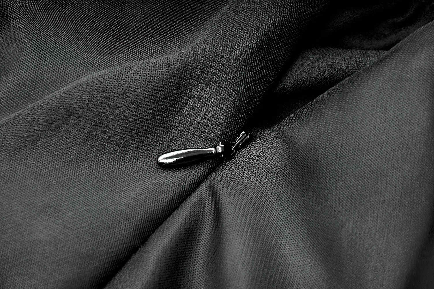 Close-up of a sleek black fabric with a stylish zipper, perfect for elegant gothic dress detailing.