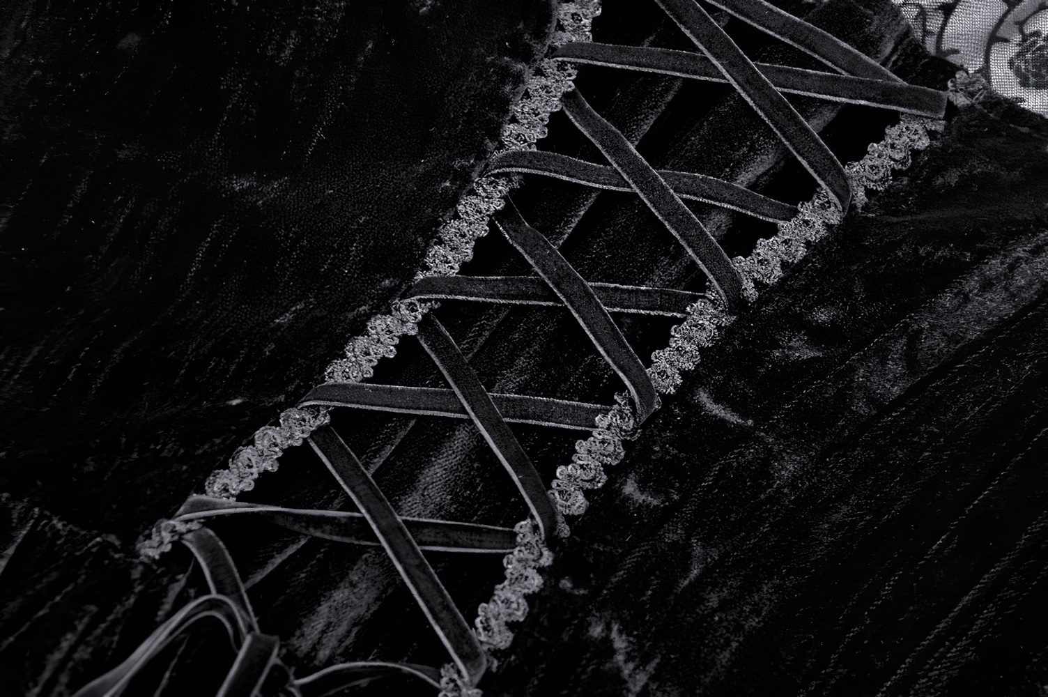 Close-up of intricate lace detailing on a chic black gothic dress, showcasing elegant cross-lacing and vintage charm.