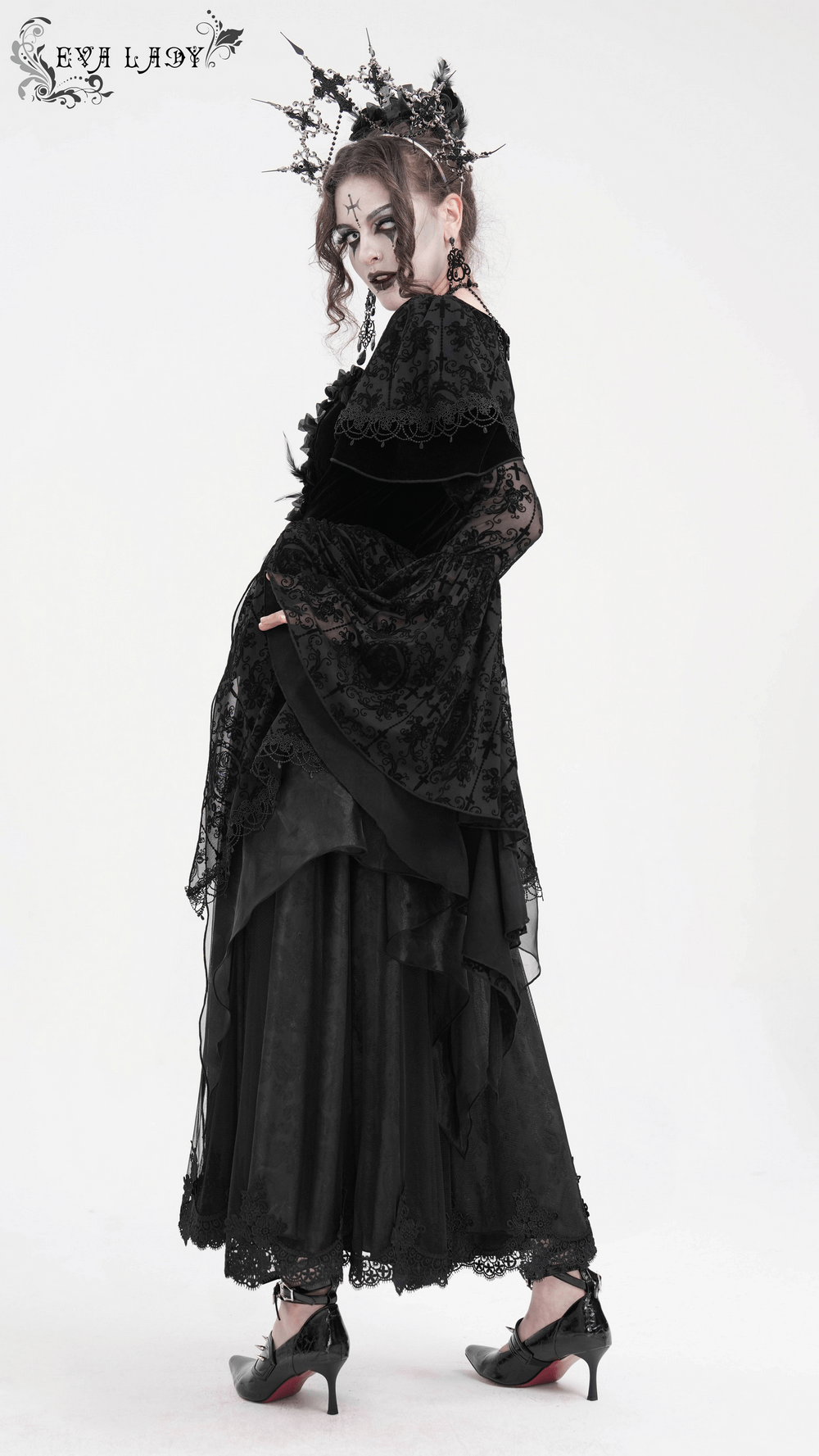 Elegant gothic model in black lace dress with bell sleeves, floral accents, and dramatic ruffled skirt for a darkly enchanting look.