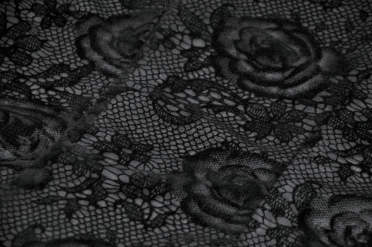 Close-up of intricate lace fabric featuring rose patterns for the Chic Lace Sheer Top with Ruffled Off Shoulder Design.