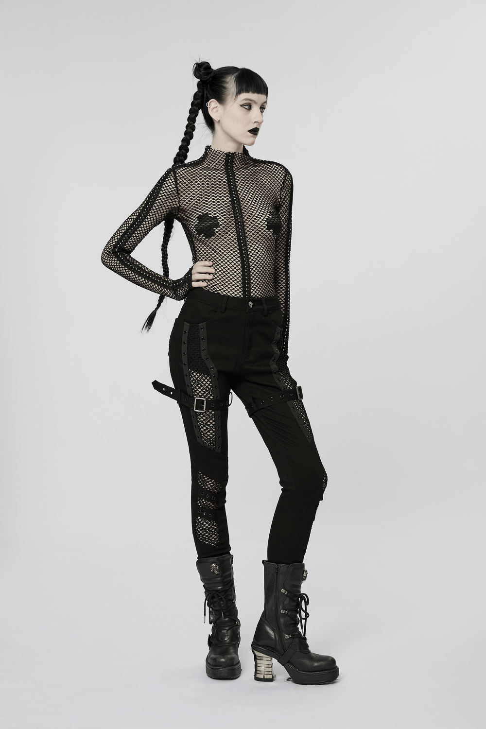 Chic gothic fashion with mesh insert trousers and a fitted top, showcasing edgy punk style and bold accessories.
