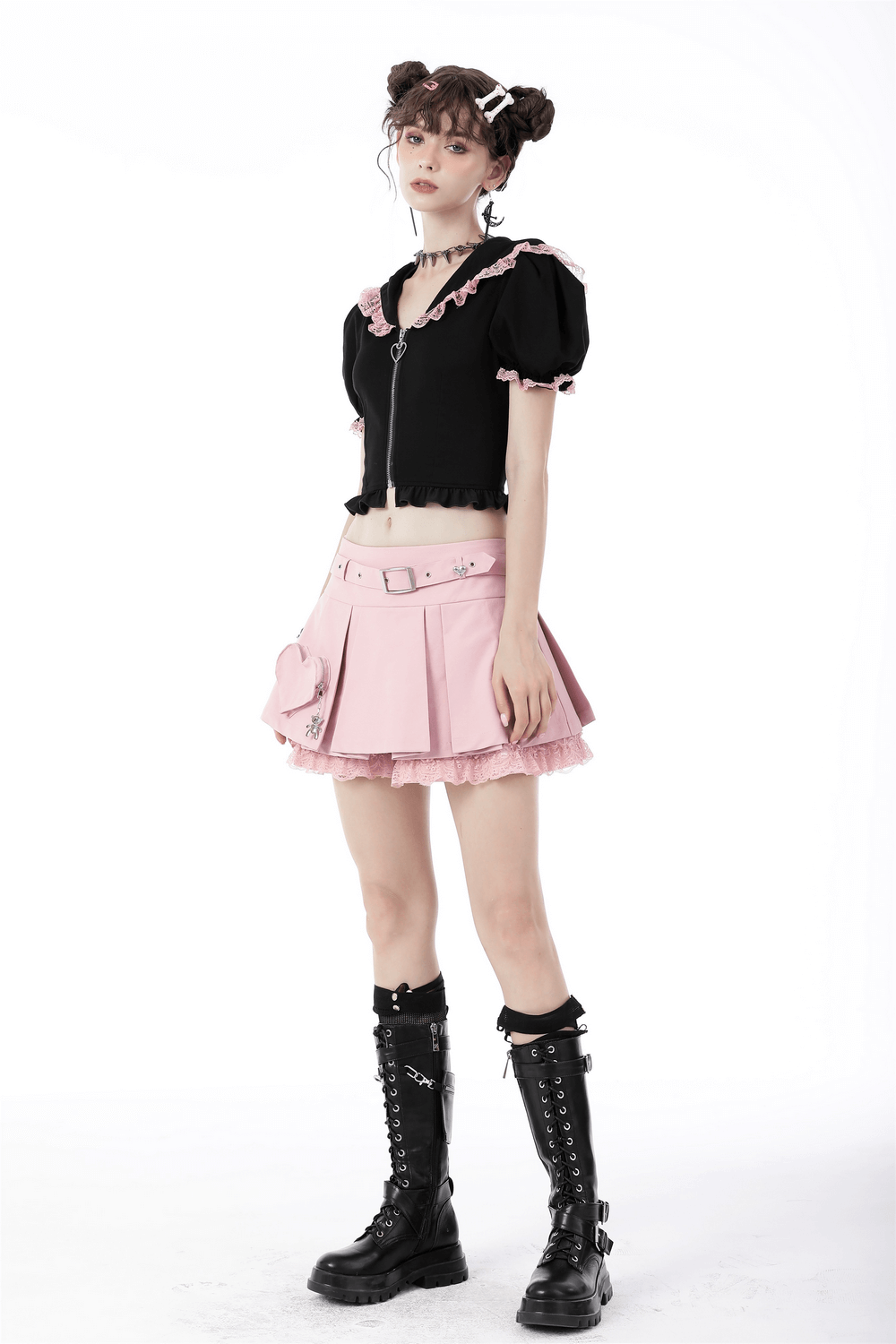 Chic pastel pink pleated mini skirt with lace and heart detail, styled with a black cropped top and combat boots.