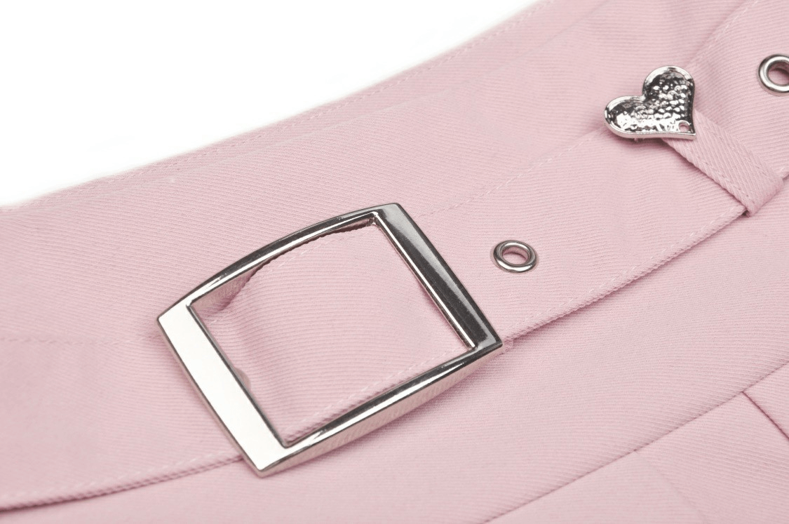 Close-up of a chic pink pleated skirt's silver belt buckle and heart detail, perfect for stylish outfits.