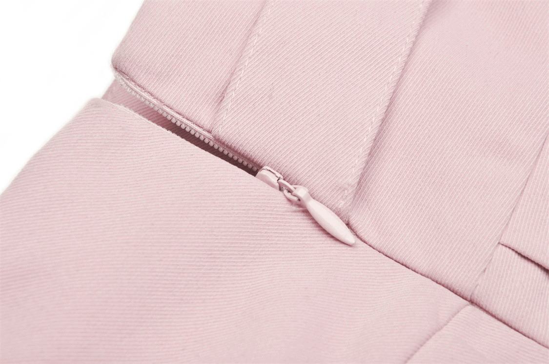 Close-up of chic pink pleated skirt zipper detail, showcasing stylish design and pastel hue.