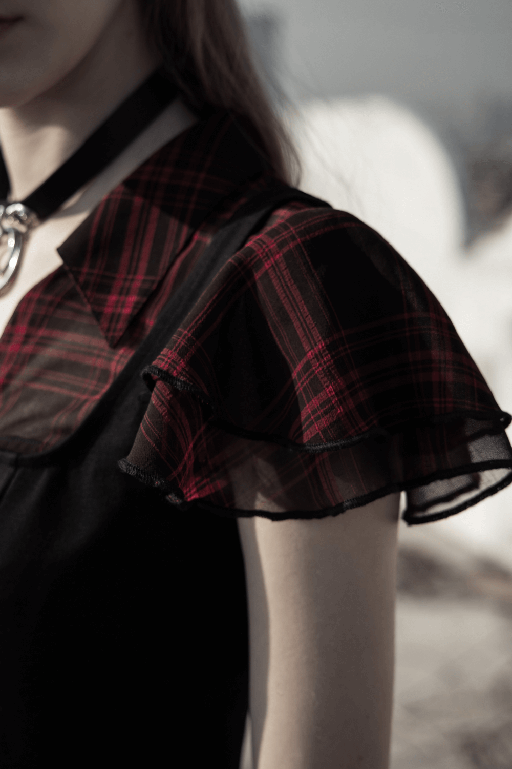 Close-up of falbala sleeve detailing on a chic plaid A-Line dress with black fabric and a stylish collar.