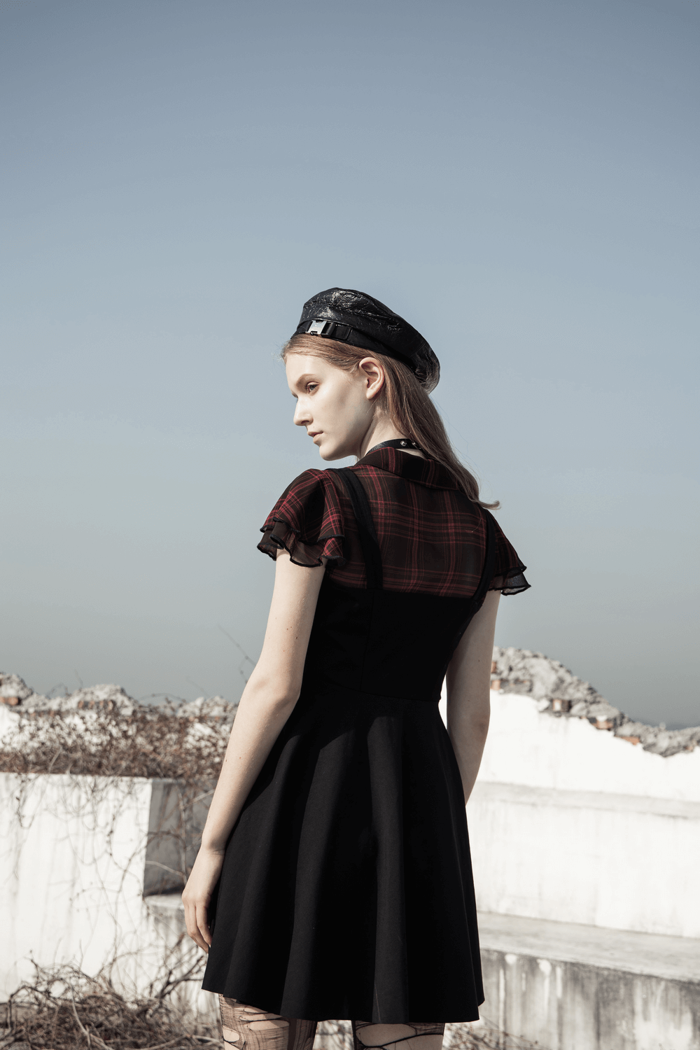 Back view of a model in a chic plaid A-line dress with falbala sleeves and stylish rivet details, showcasing a gothic vibe.