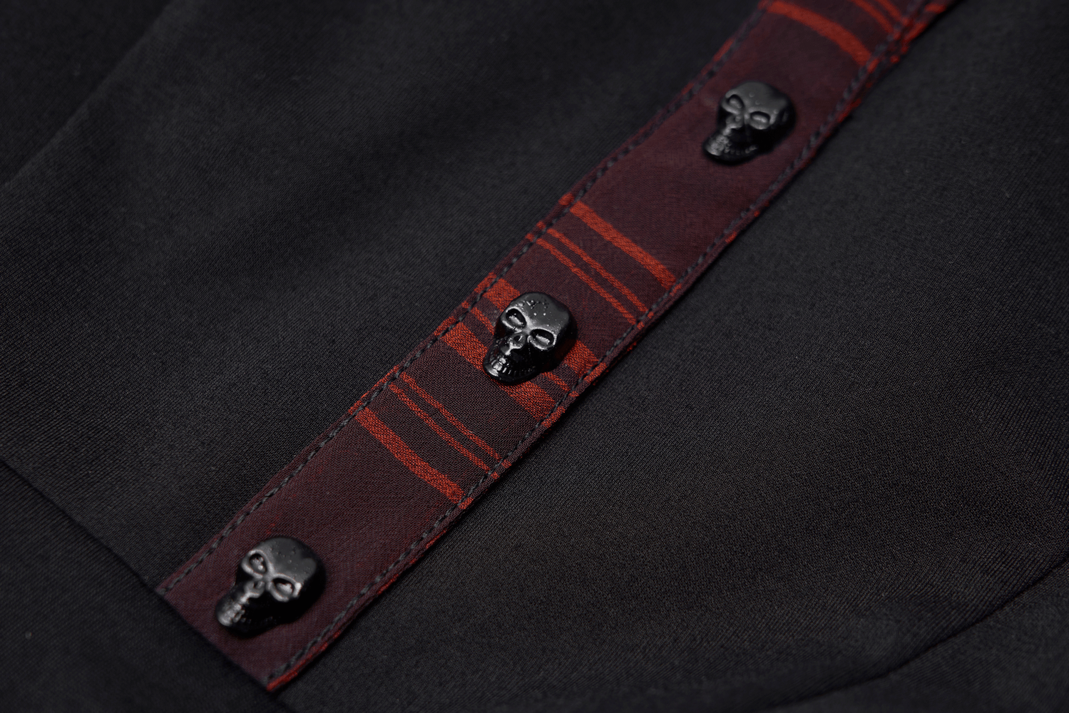Close-up of skull rivets on a chic plaid A-line dress, adding a gothic flair to the stylish design.