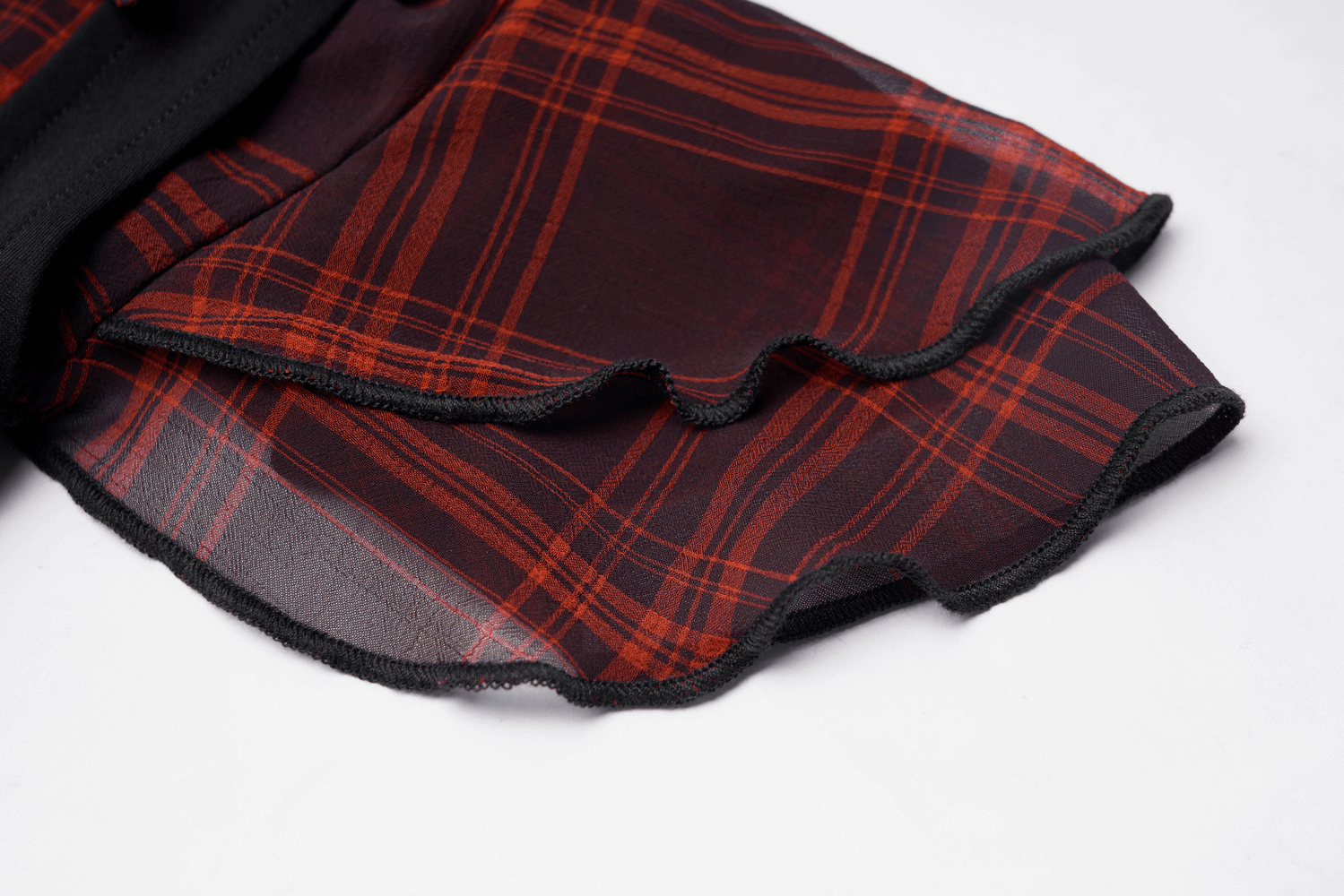Close-up of a chic plaid fabric in deep red tones with elegant ruffled edges, perfect for a gothic A-line dress.