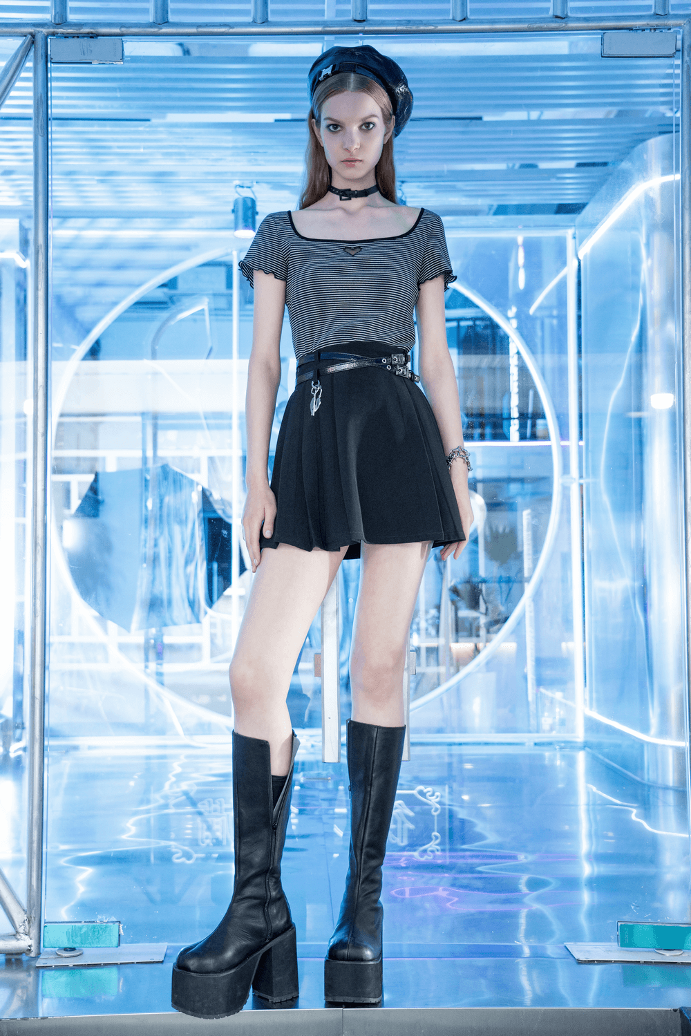 Chic pleated skirt with detachable belt and pendant, styled with a trendy top and edgy knee-high boots.