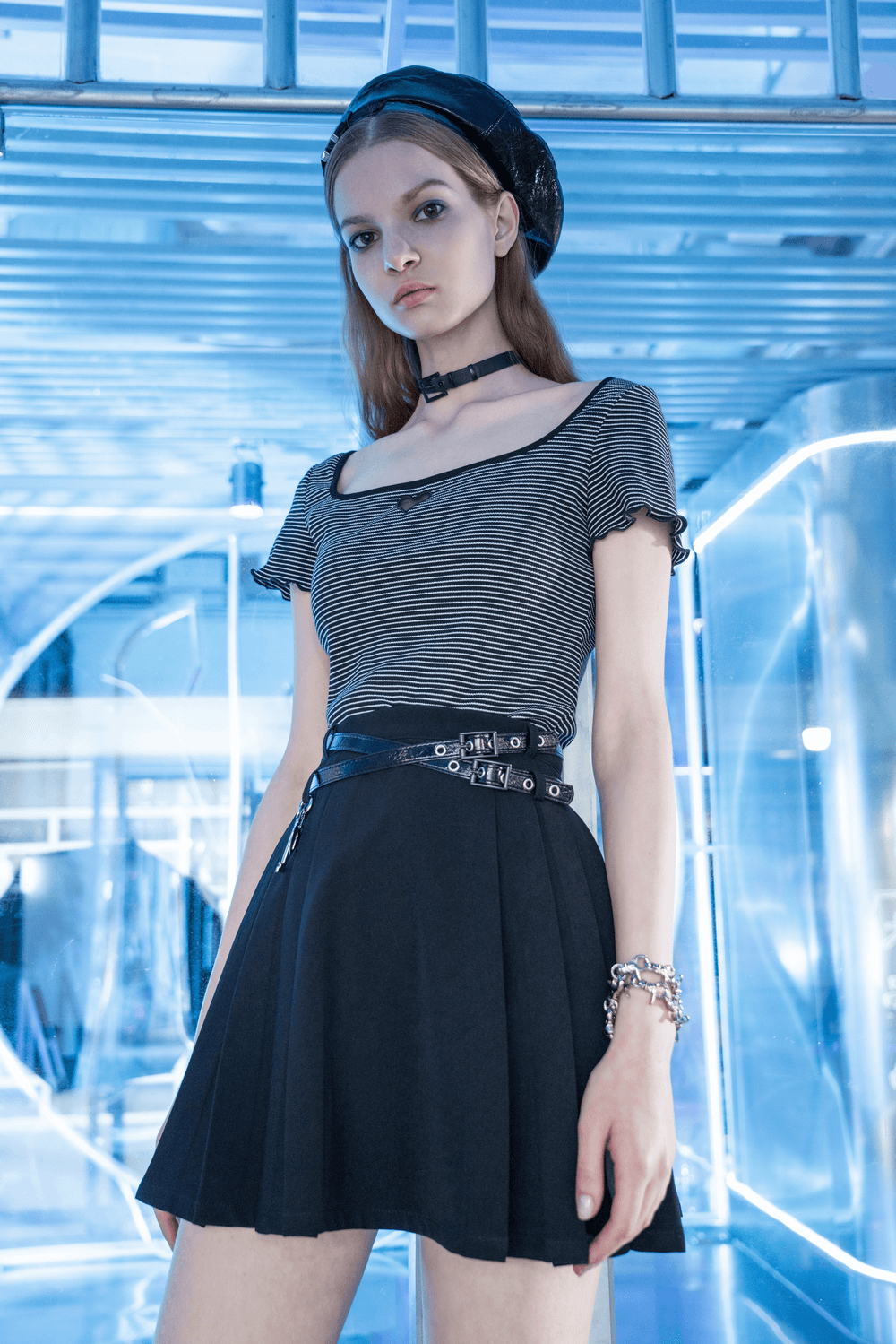 Chic model wearing a pleated skirt with detachable belt and pendant in a stylish urban setting.