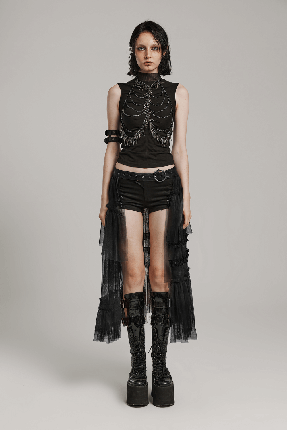 Dramatic black mesh half skirt layered with punk-inspired accessories and bold platform boots.