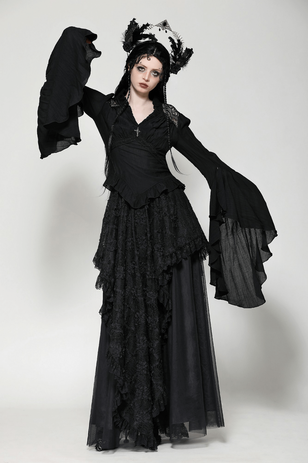 Gothic elegance with black ruffled flare sleeved top featuring lace details and a vintage brooch, perfect for alternative fashion lovers.