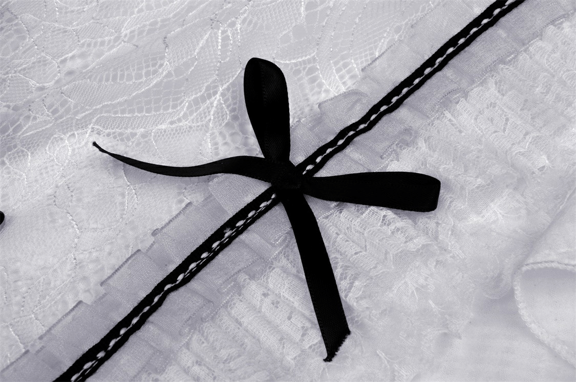 Close-up of black ribbon and lace details on a chic white A-line dress, showcasing elegant design and craftsmanship.