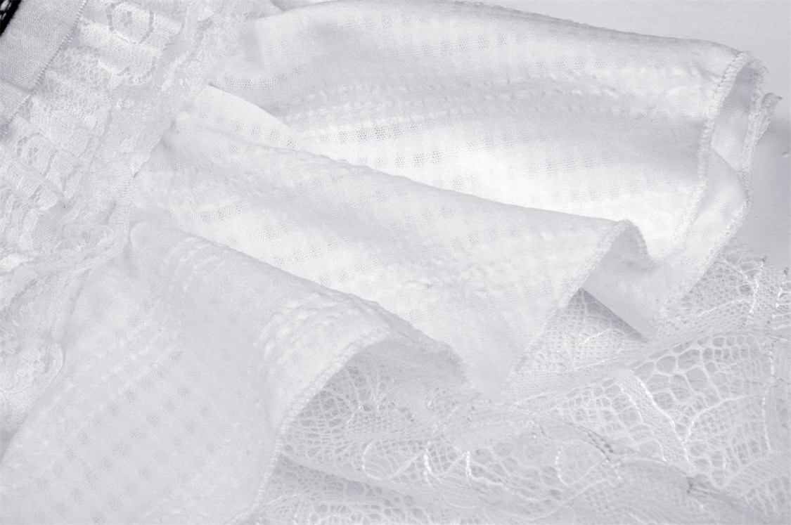 Close-up of elegant white fabric featuring lace trim and texture, perfect for a chic dress.