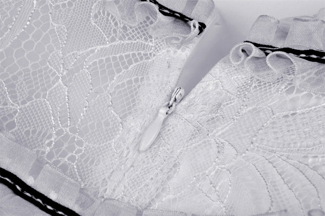Close-up of delicate lace and ribbon trim on a chic white dress, showcasing elegant details and craftsmanship.