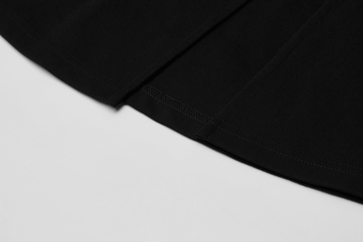 Close-up of the hem detail on a chic black v-neck dress with a high slit.