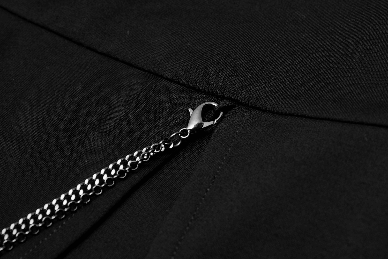 Close-up of a stylish black dress zipper with a detachable chain accent for a chic look.