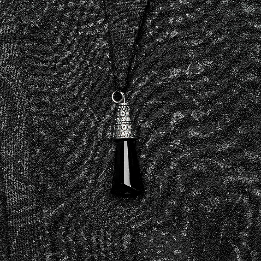 Close-up of a crystal pendant on a black chiffon cloak showcasing gothic fashion details.
