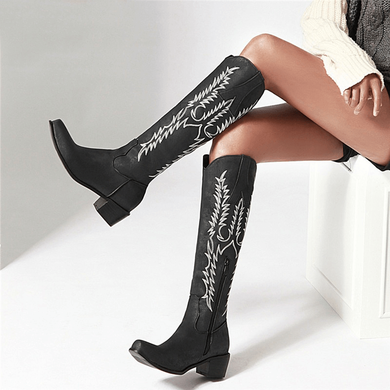 Classic knee-high black boots with mid heels and embroidered patterns, perfect for retro floral and denim outfits.