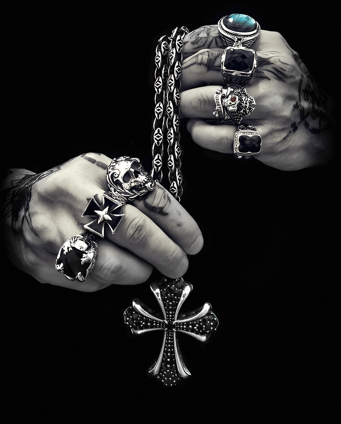Close-up of hands with ornate rings holding a cross pendant.