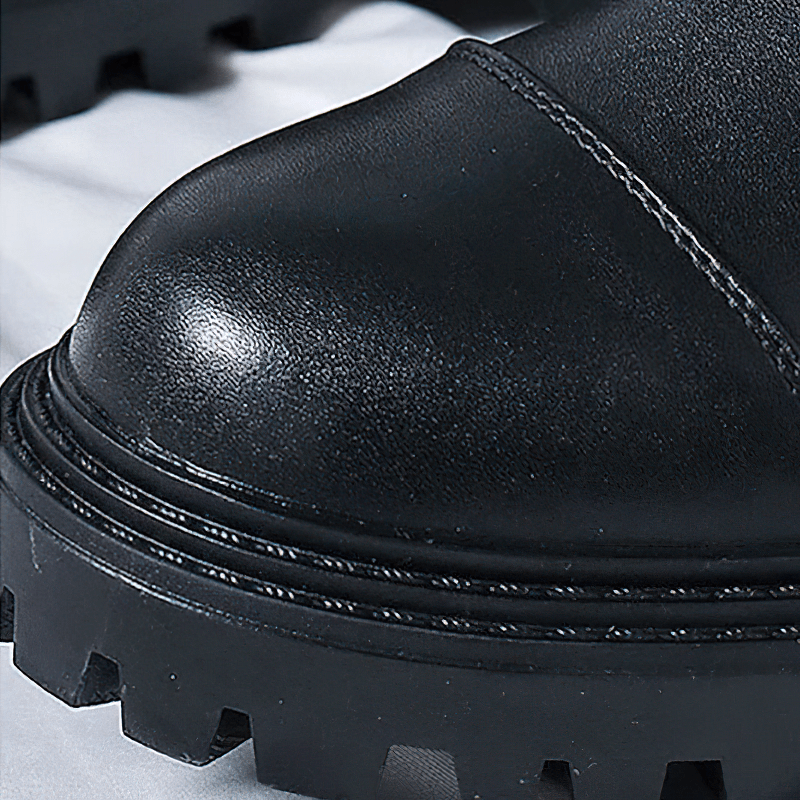 Close-up of black lace-up ankle boots with a textured rubber sole, showcasing quality craftsmanship and stylish design.