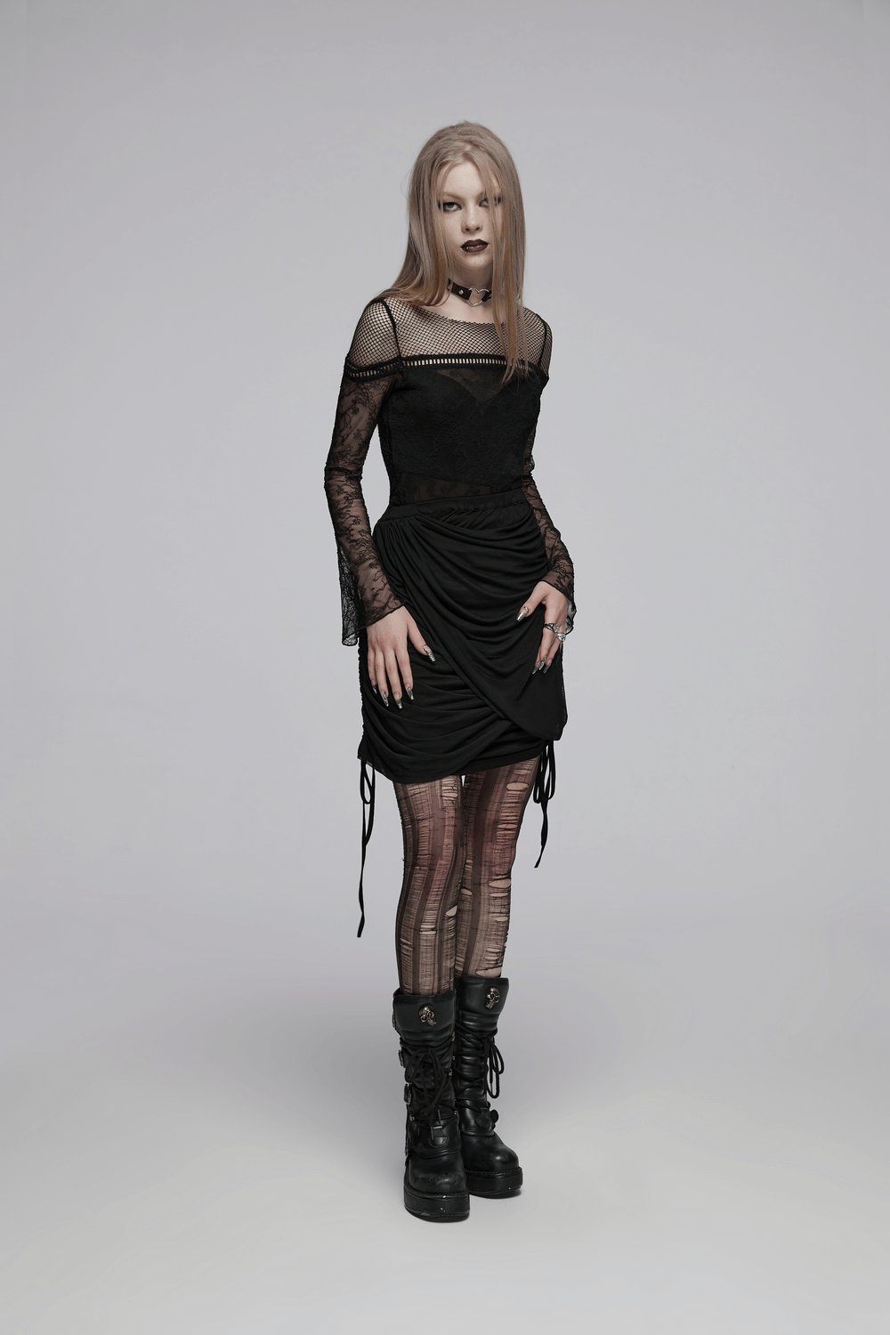 Fashion-forward model in a black stylish pleated dress with edgy accessories and bold makeup.