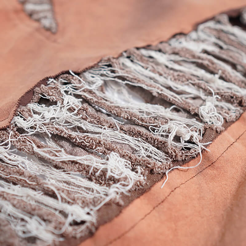 Close-up of trendy oversize hole-ripped detail on vintage cotton t-shirt fabric.