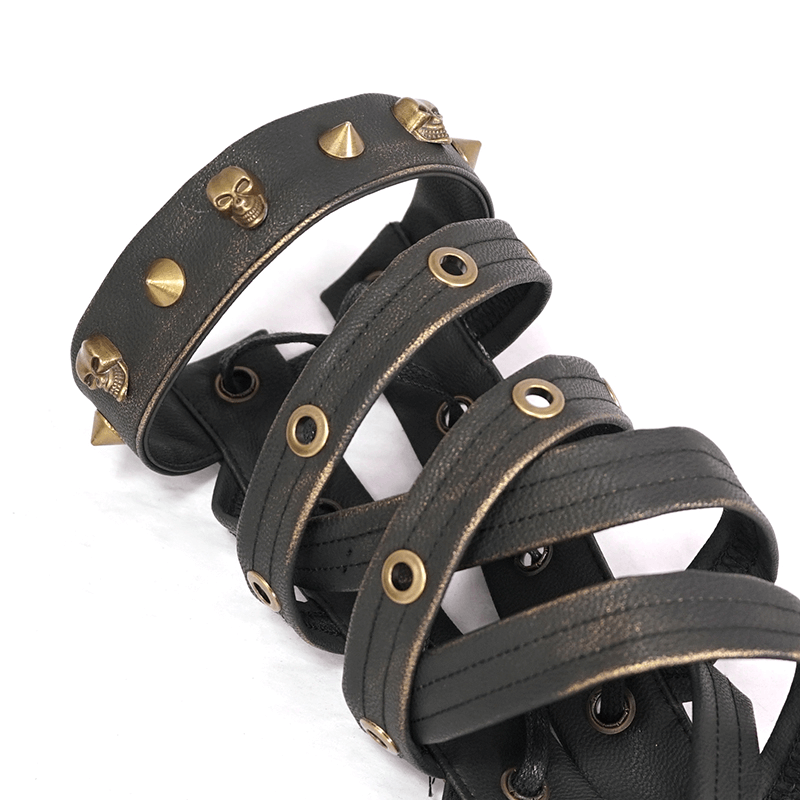 Close-up of stylish black PU leather steampunk gloves with bronze skulls and spikes, perfect for punk fashion.