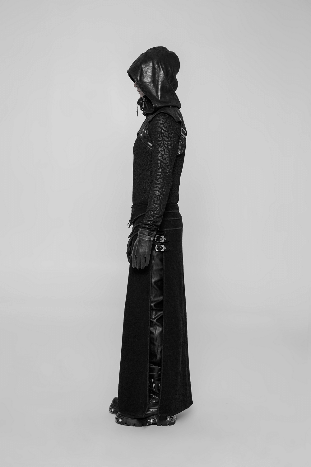Side view of a model wearing a crack skin stitched punk hood, black top, and long skirt with edgy details.