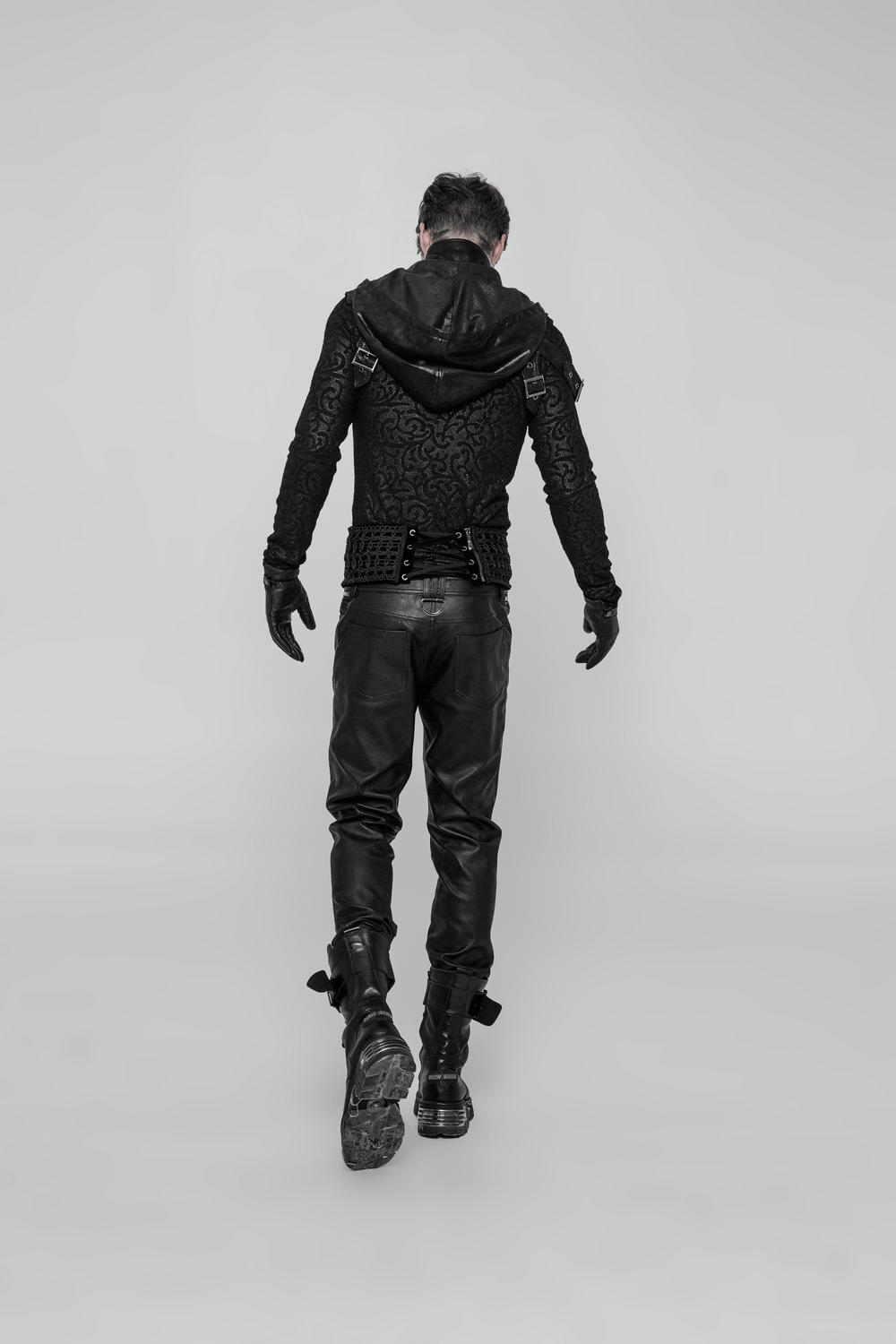 Model walking away in a cracking skin stitched punk hood with patch detail and leather pants, showcasing an edgy style.