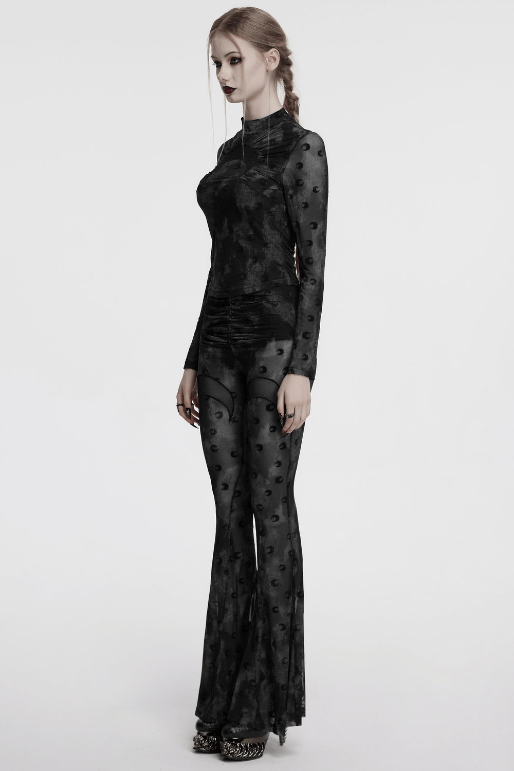 Model wearing crescent moon printed mesh flare pants with pleated waist strap and long-sleeve top.