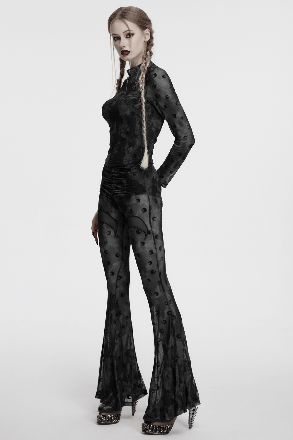 Model wearing black crescent moon mesh flare pants with pleated waist strap, featuring a bold and mystical design.