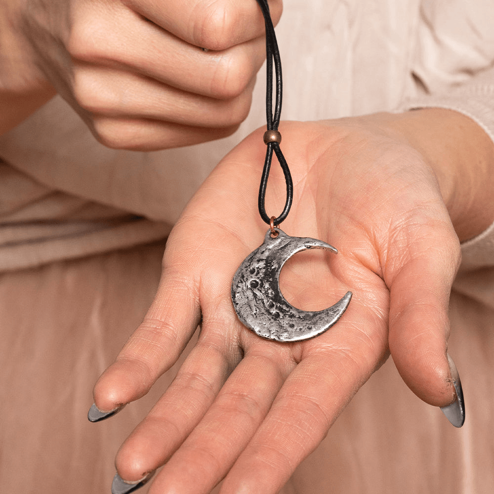 Crescent Moon Pendant Necklace with Pewter Talisman held in a hand, showcasing its intricate design.