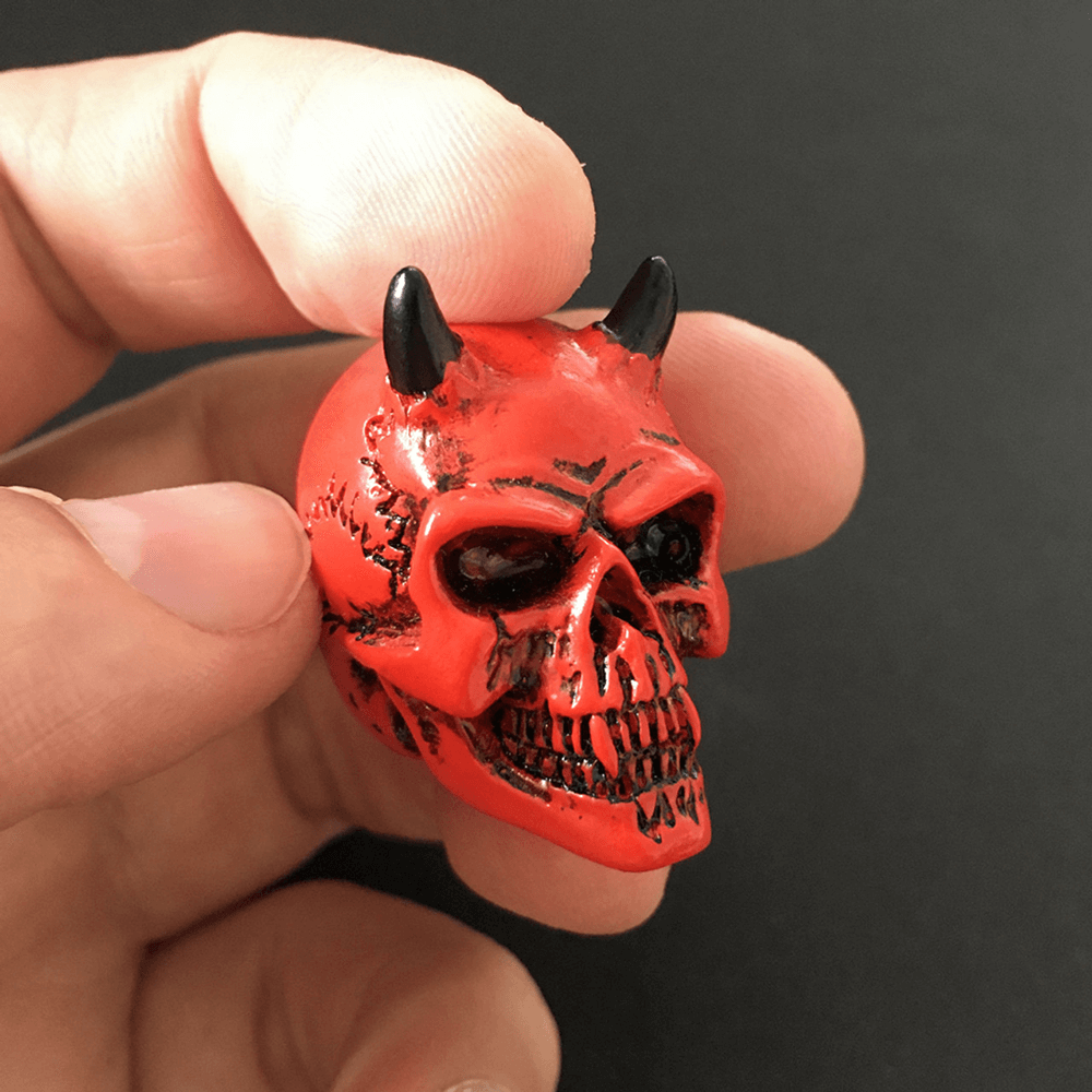 Handheld crimson demon skull miniature with horns, detailed resin figure for collectors and unique gifts.
