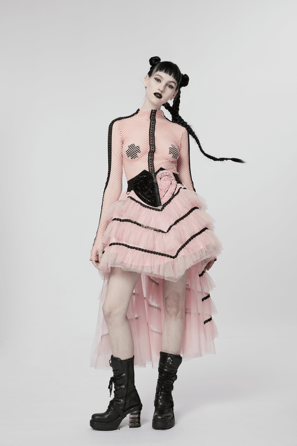 Cute punk girl in a pink ruffled mesh skirt with black accents and stylish boots, showcasing edgy fashion.