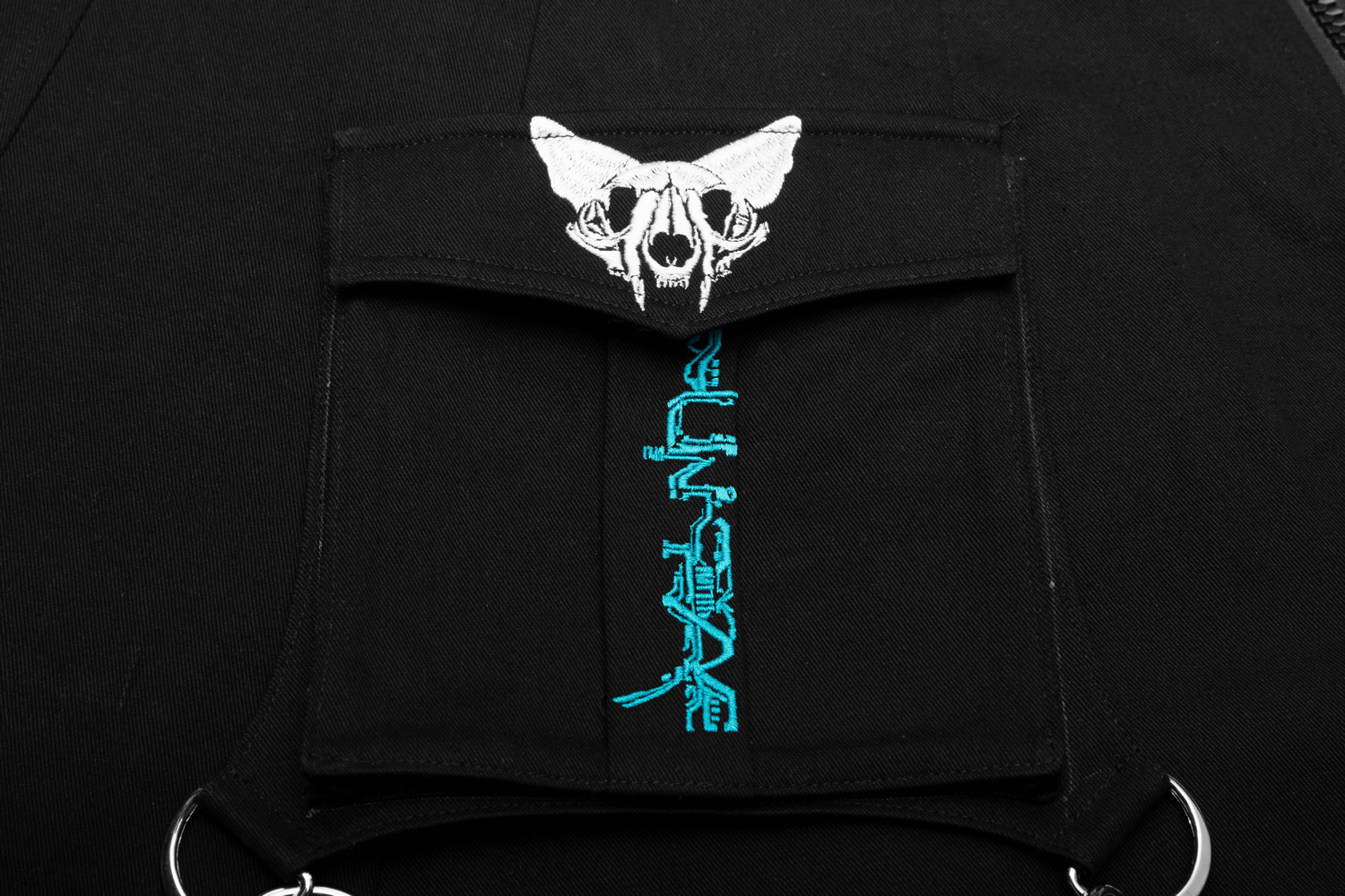Close-up of black fabric featuring skull and butterfly embroidery with blue text design.