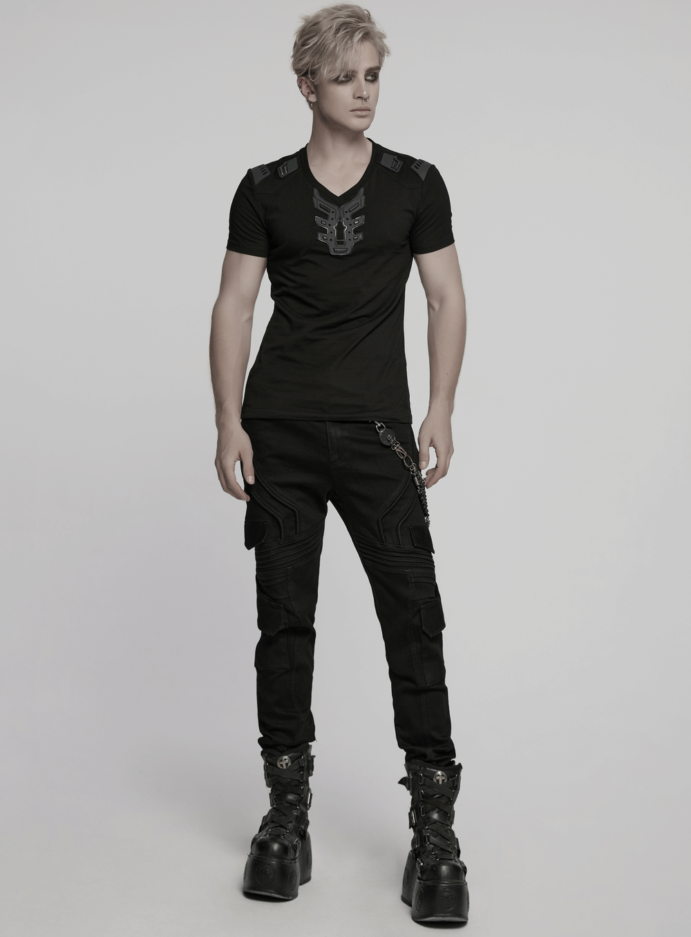 Futuristic cyberpunk T-shirt with V-shaped shoulders and 3D rubber patch, styled with black cargo pants and chunky boots.