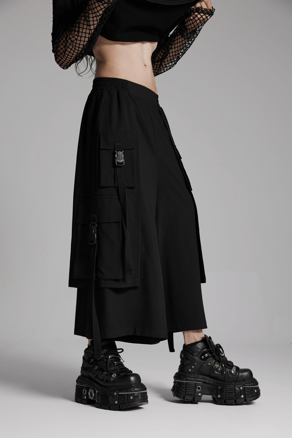 Cyberpunk black wide-leg pants with elastic waistband, featuring unique cargo pockets and edgy footwear.