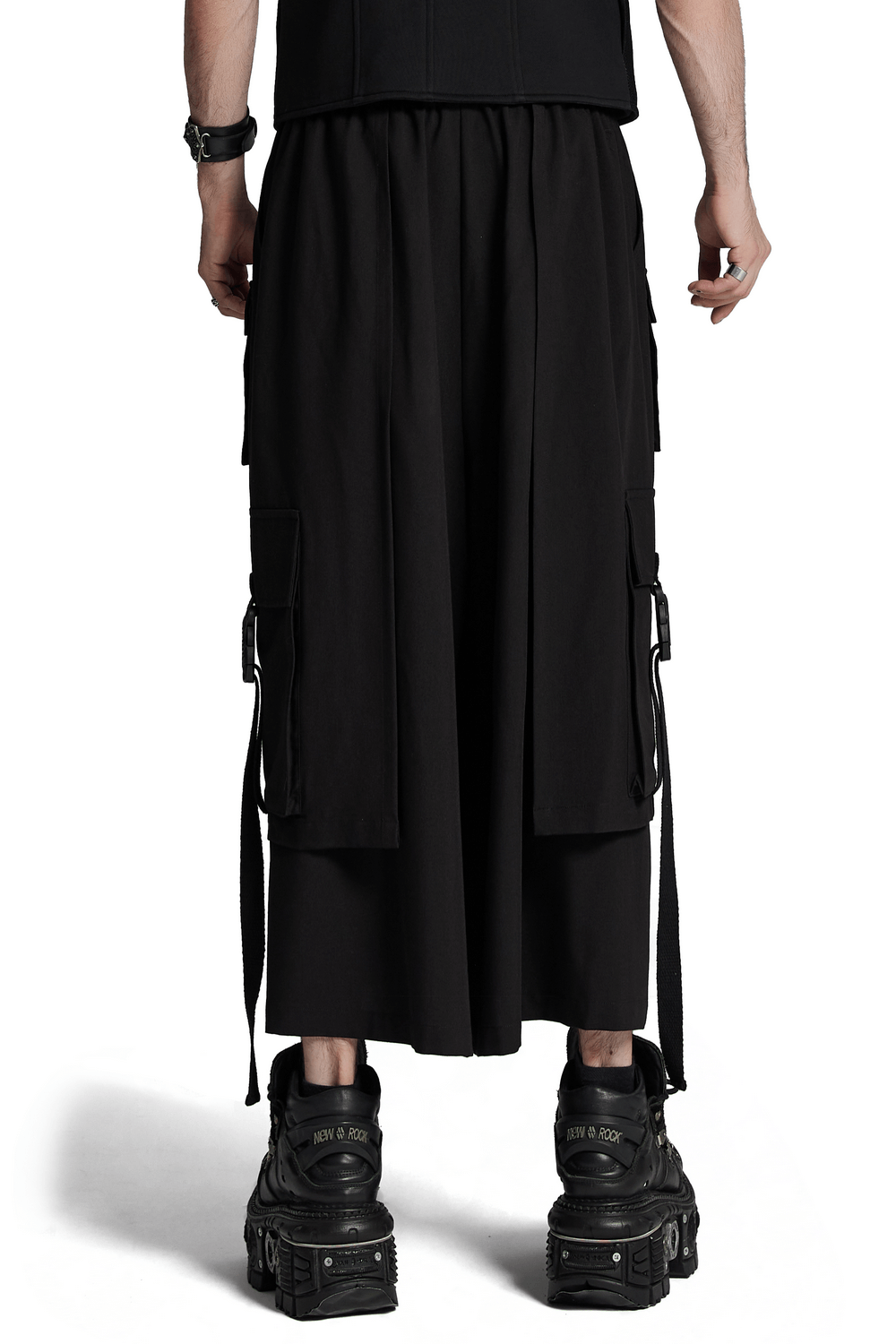 Back view of edgy cyberpunk black wide-leg pants with elastic waistband and side loops, paired with chunky black boots.