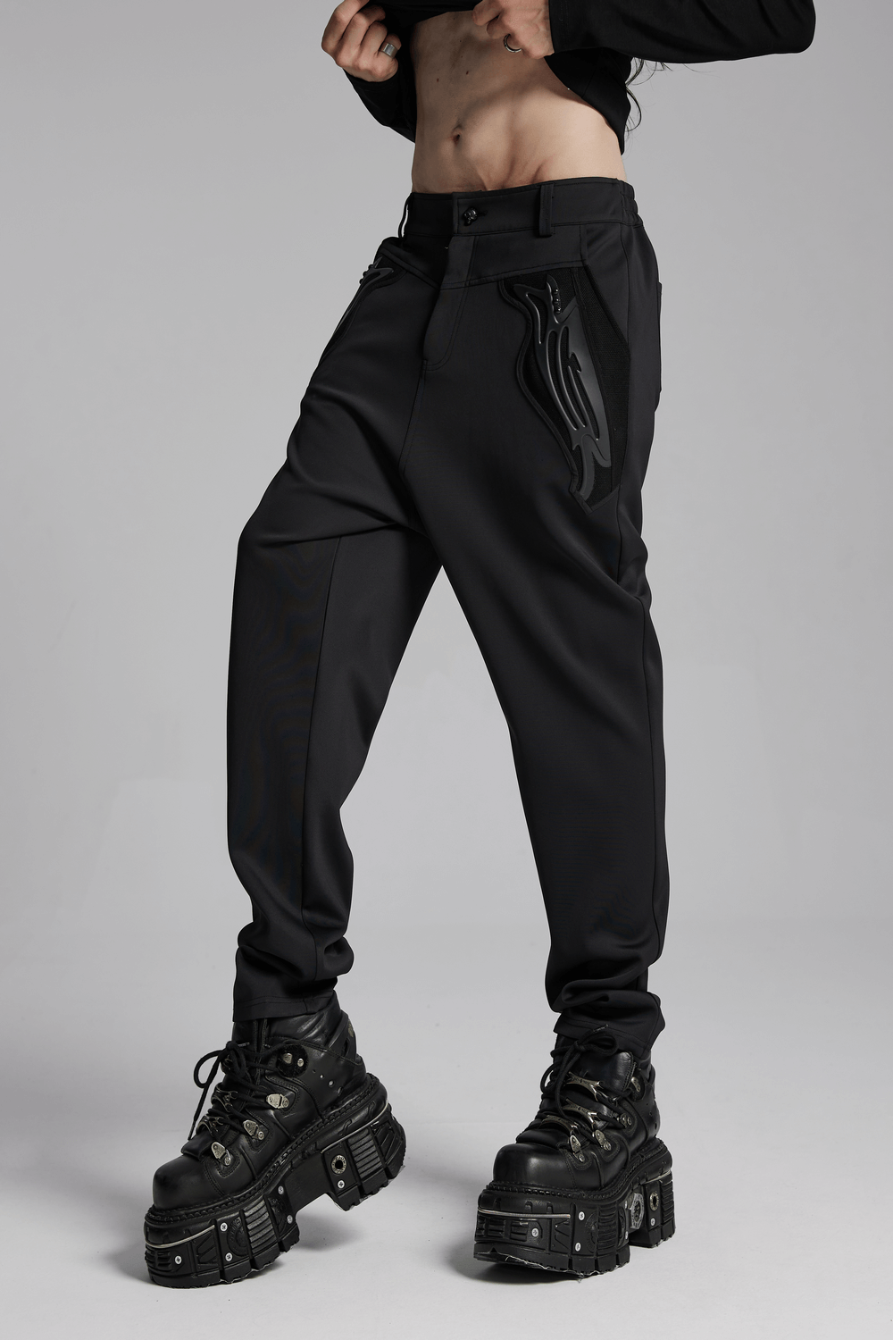 Cyberpunk-inspired black knitted pants with riveted pockets and 3D details, styled with chunky platform boots.