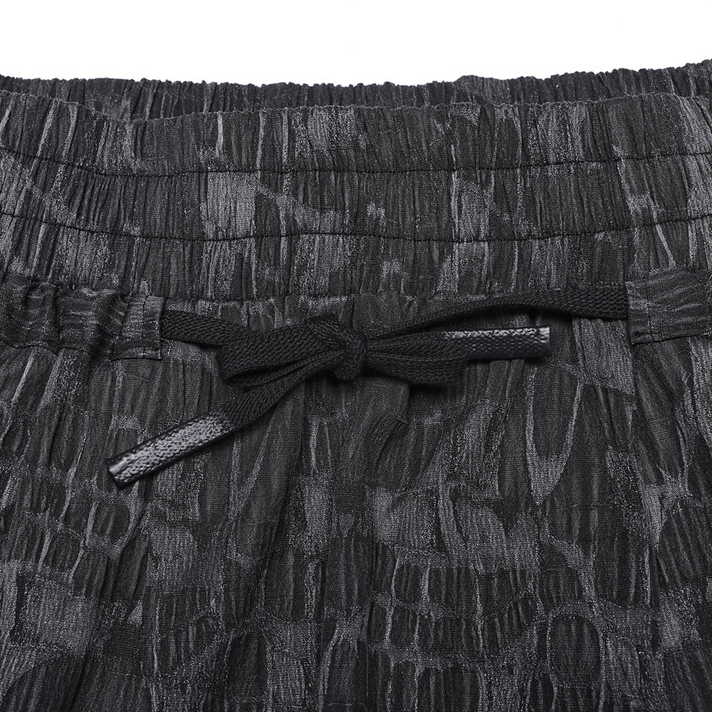 Close-up of the elastic waistband and textured snake print of men's cropped trousers.