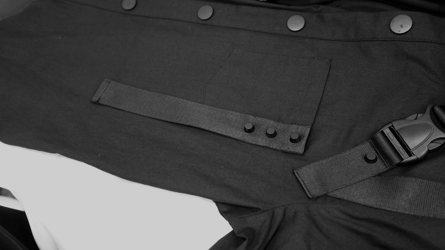 Close-up of a cyberpunk style black shirt showcasing straps and buttons, perfect for a modern gothic wardrobe.