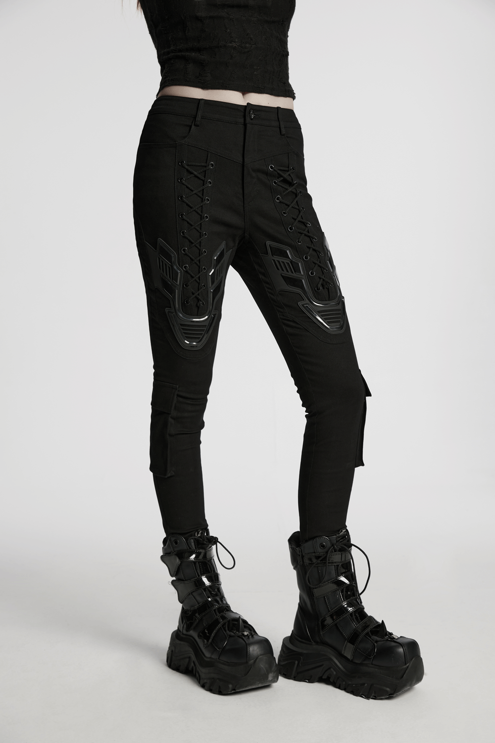 Cyberpunk tight trousers with 3D armor patch, eyelet drawstrings, and calf pockets, paired with chunky black boots.