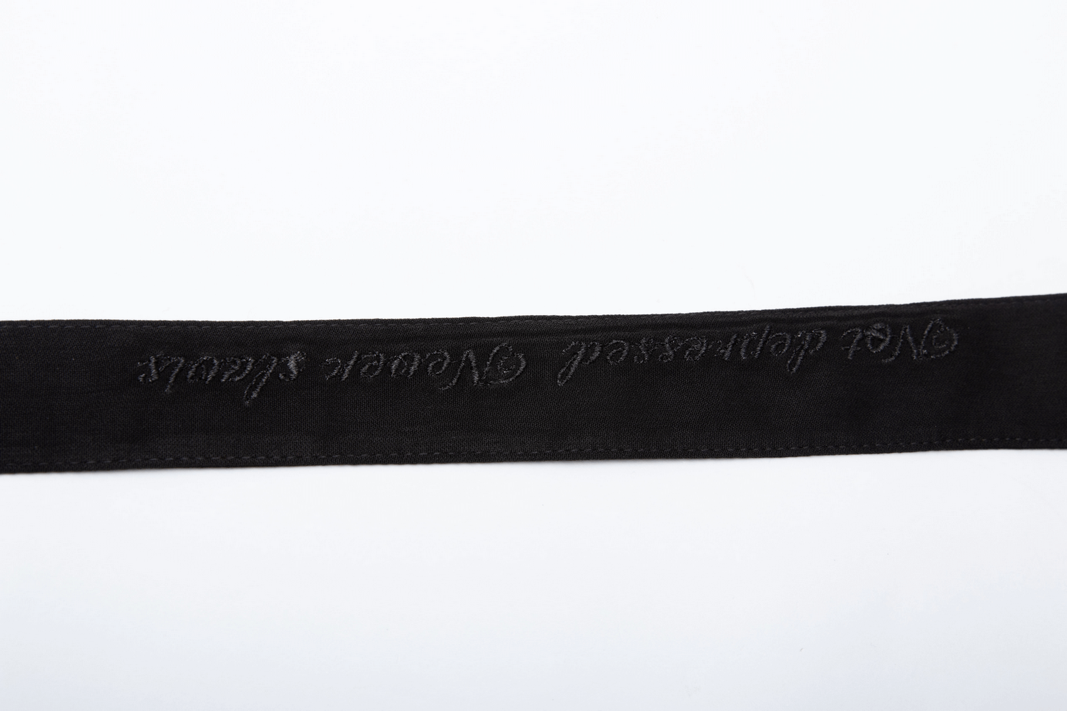 Close-up of a black embroidered belt featuring a Gothic slogan for an edgy fashion statement.