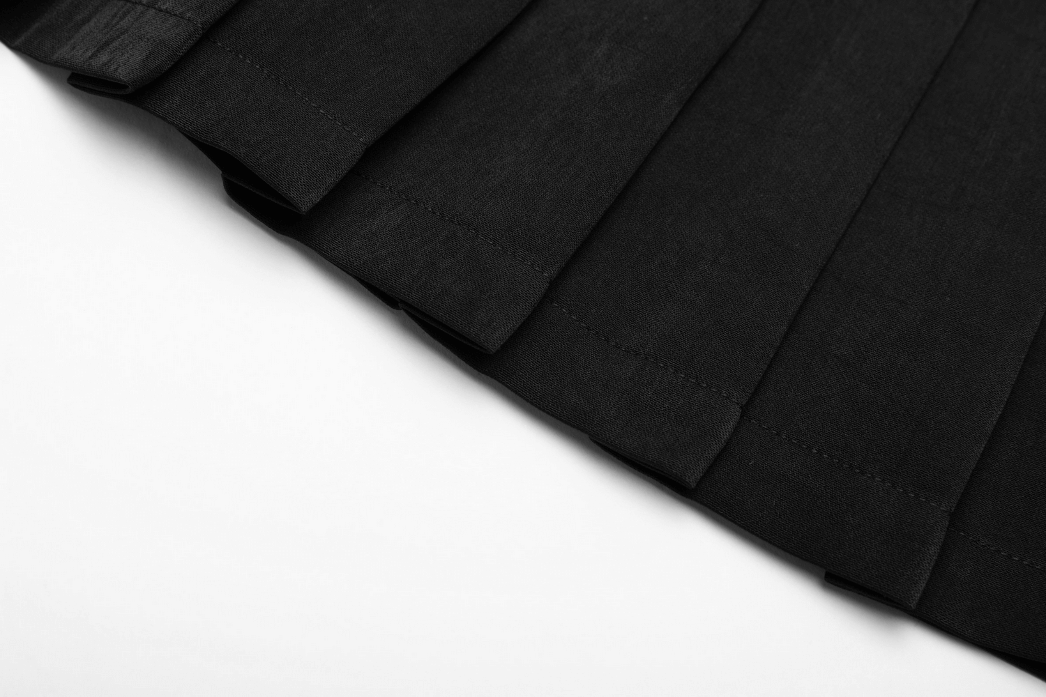 Close-up of a black pleated skirt showcasing elegant folds and a smooth texture, perfect for pairing with edgy styles.