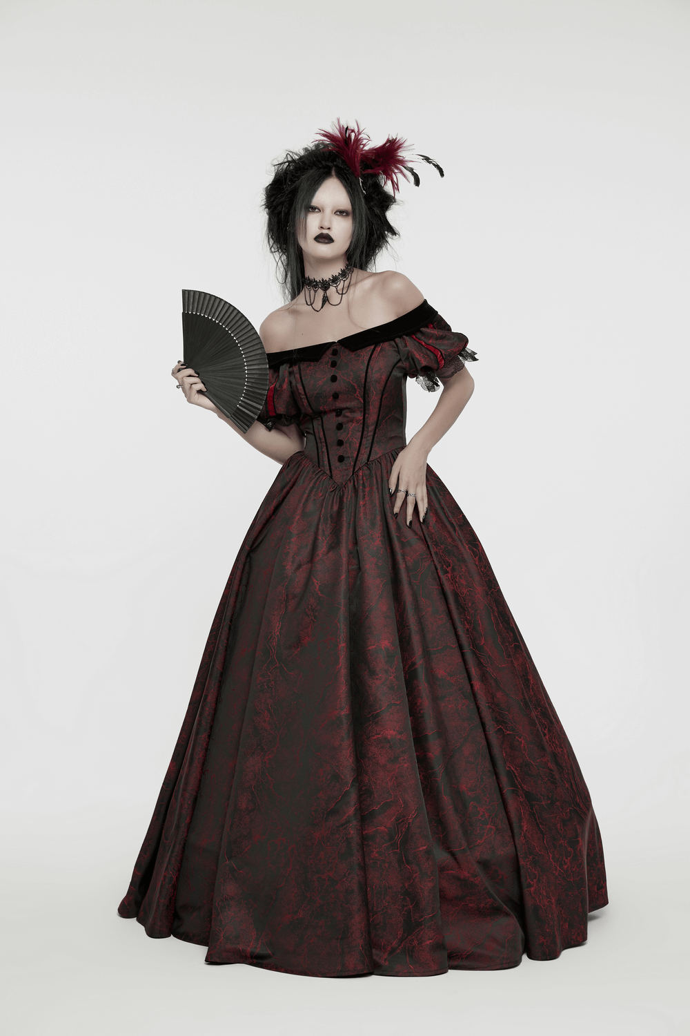 Gothic model in elegant red and black dress with fan and extravagant feather accessory, perfect for dark fashion lovers.