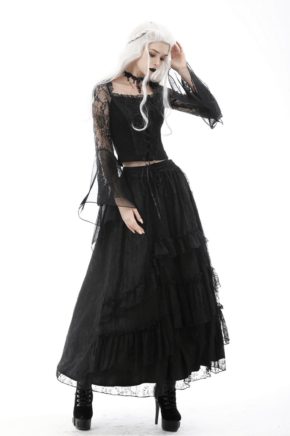 Victorian goth model in a black lace crop top and flowing mesh maxi skirt with tiered lace trim.