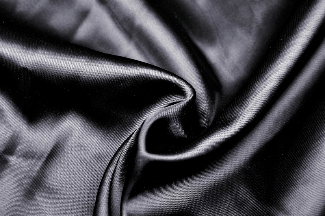 Close-up of smooth black satin fabric, perfect for elegant clothing designs and luxurious textures.
