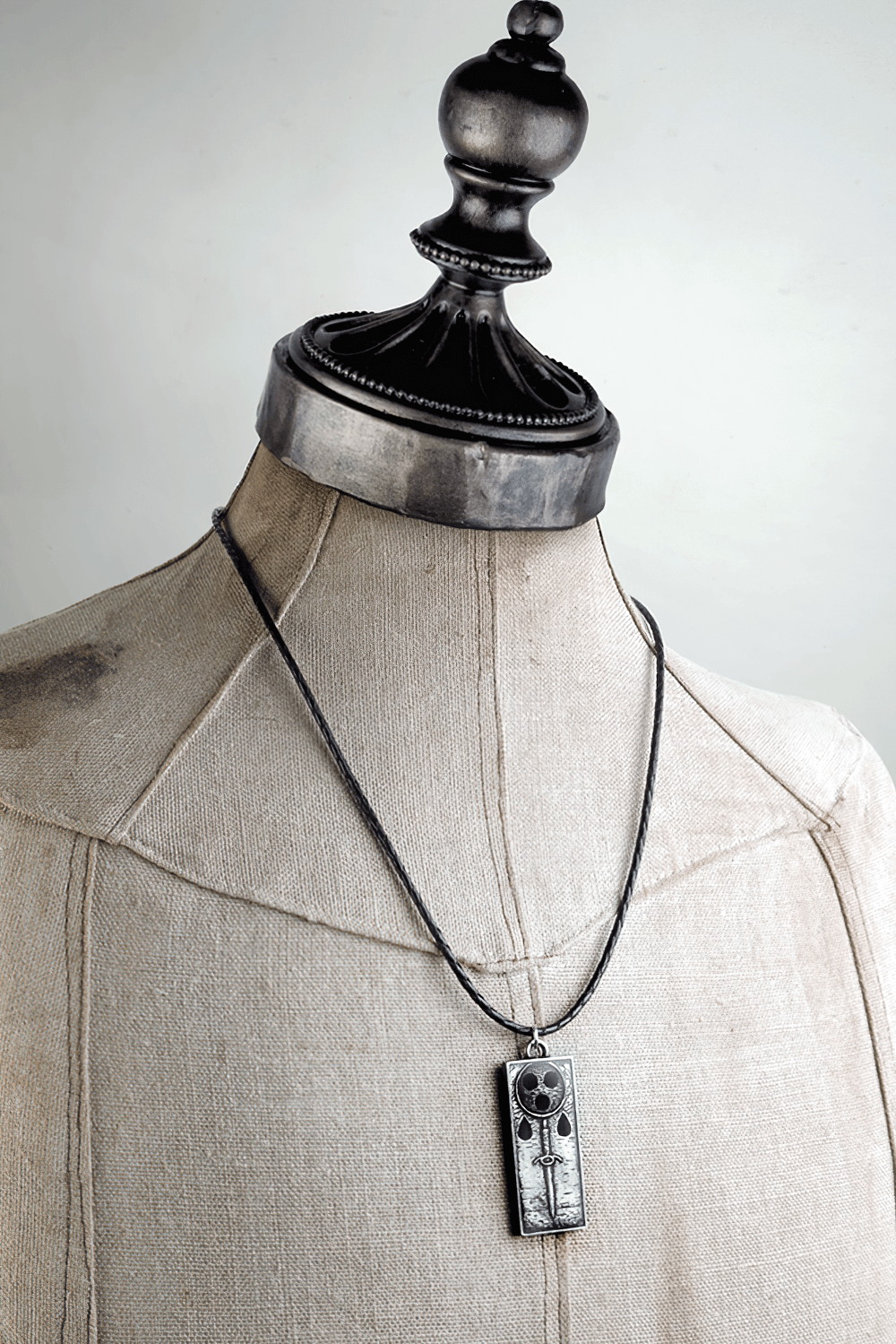 Dark Gothic Death Sigil Sword and Skull Pendant hanging on a mannequin, showcasing its intricate design.